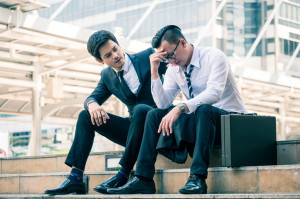 Frustrated Asian young business man sitting outdoor office after